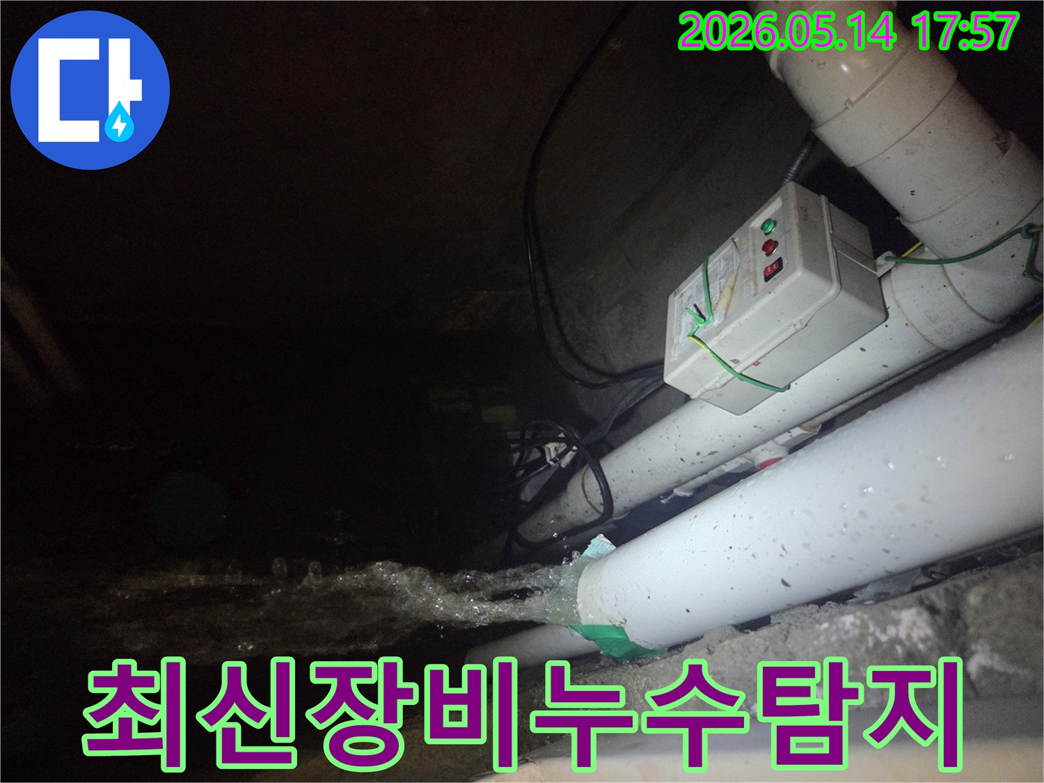 어두운 지하 공간에서-파이프에서 물이 강하게 뿜어져 나오는-누수 현장을 최신 장비로 탐지하는 모습입니다-전기 제어 박스와 배관들이 함께 보입니다.