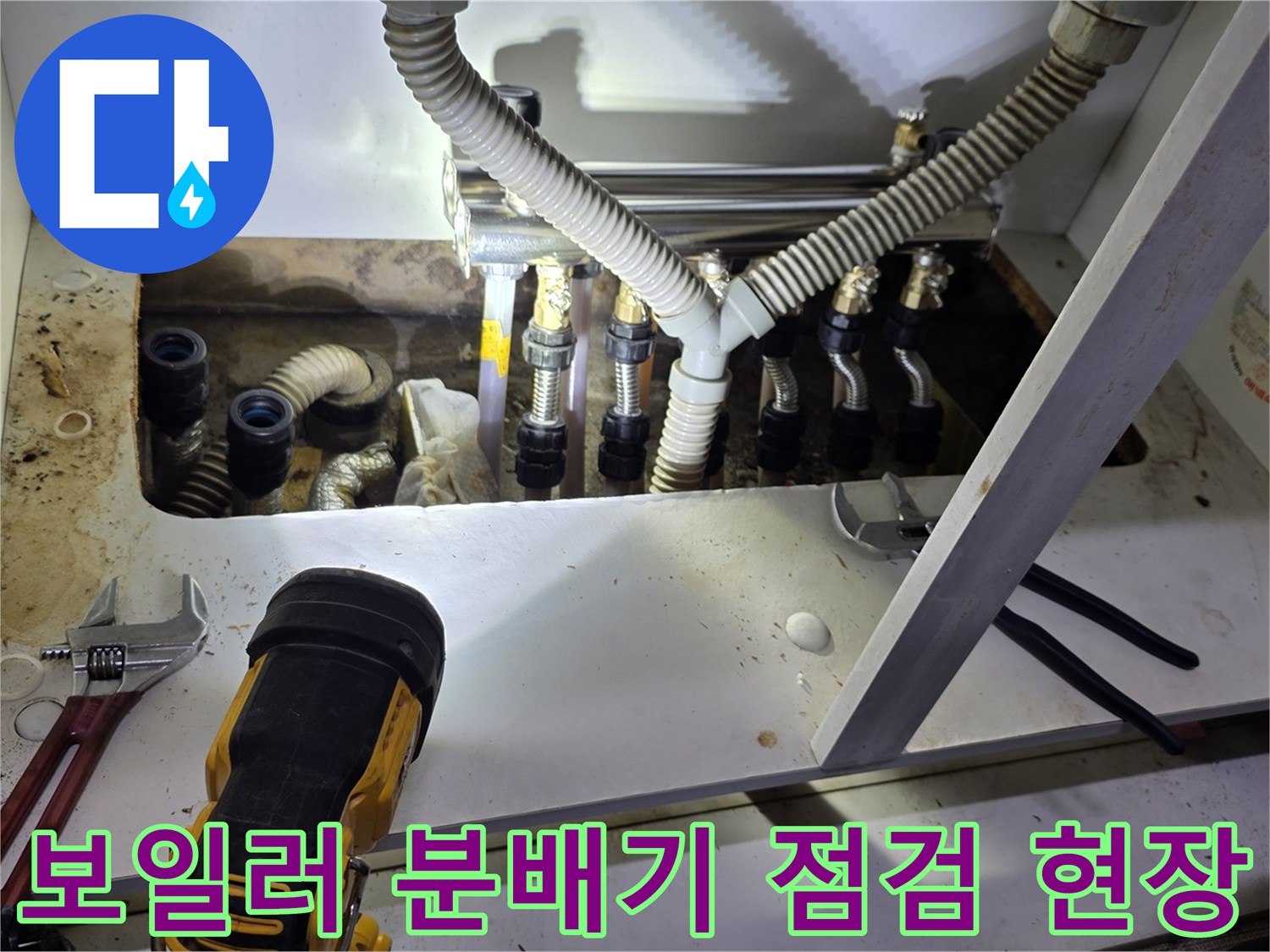 싱크대 밑 보일러 분배기와 주름관 연결 상태를 촬영한 사진