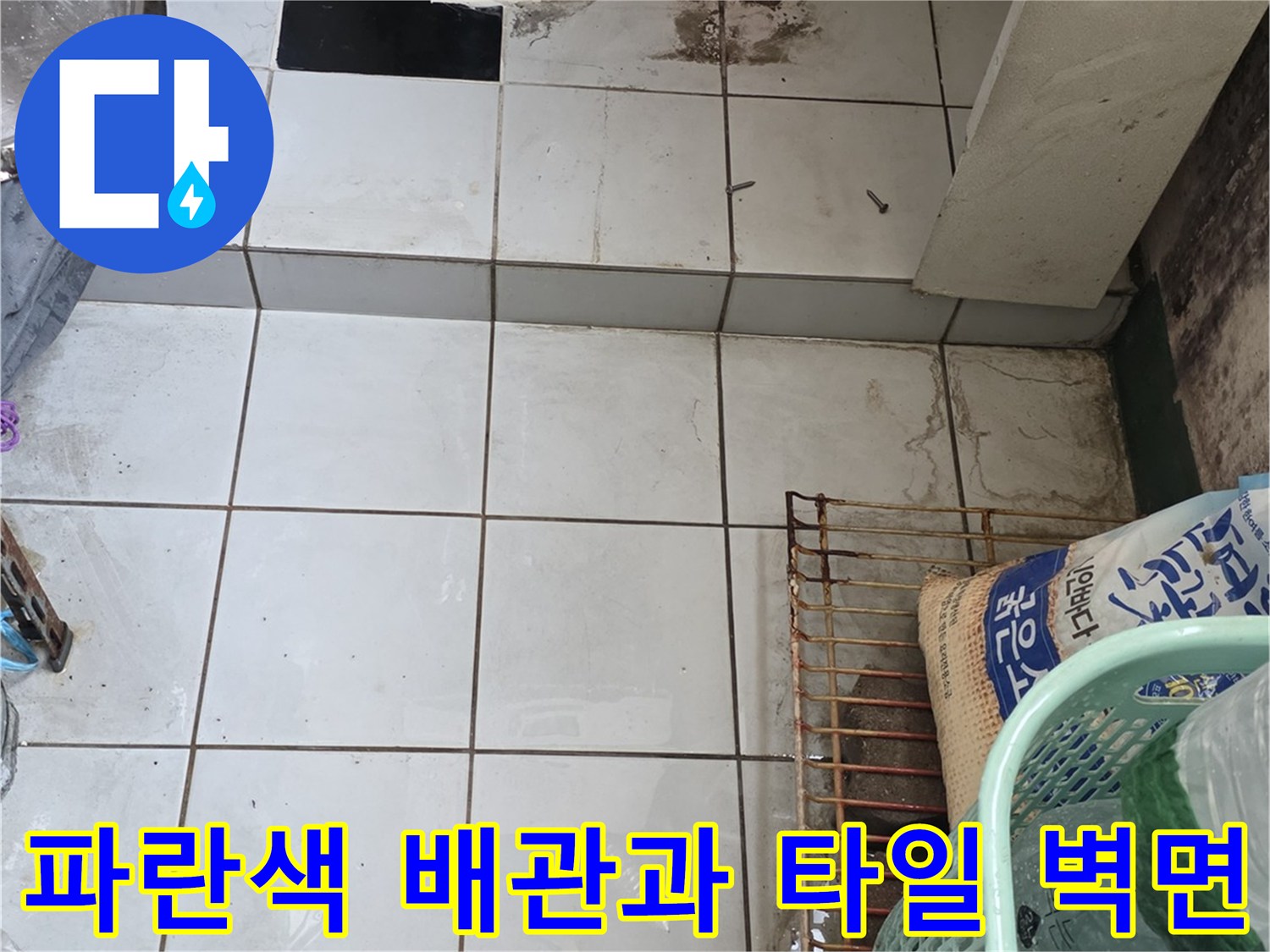 싱크대 하단부 파란색 배관 및 흰색 타일 벽면 상세 이미지