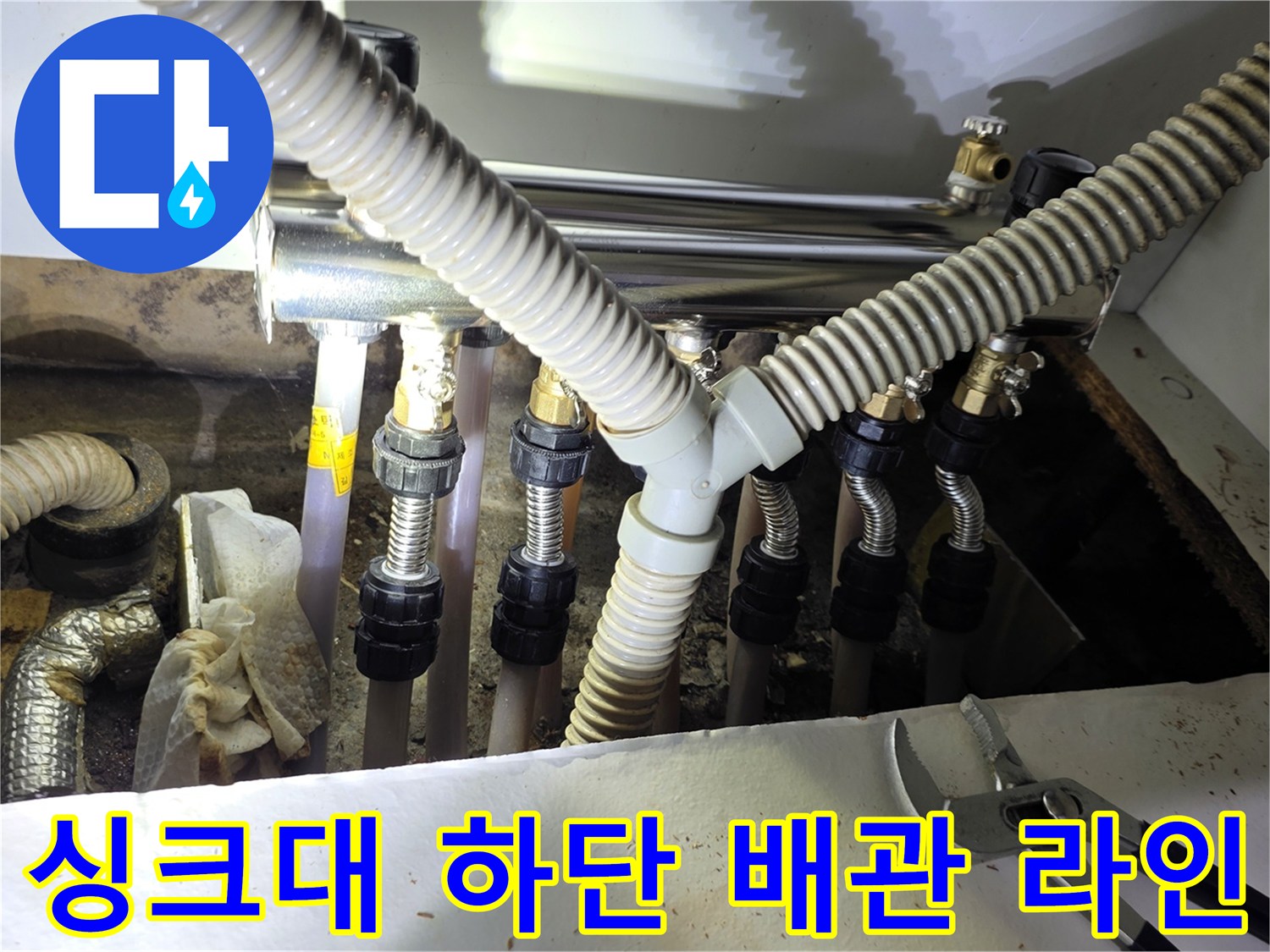 싱크대 하부장에 복잡하게 연결된 보일러 분배기 및 유연한 호스들