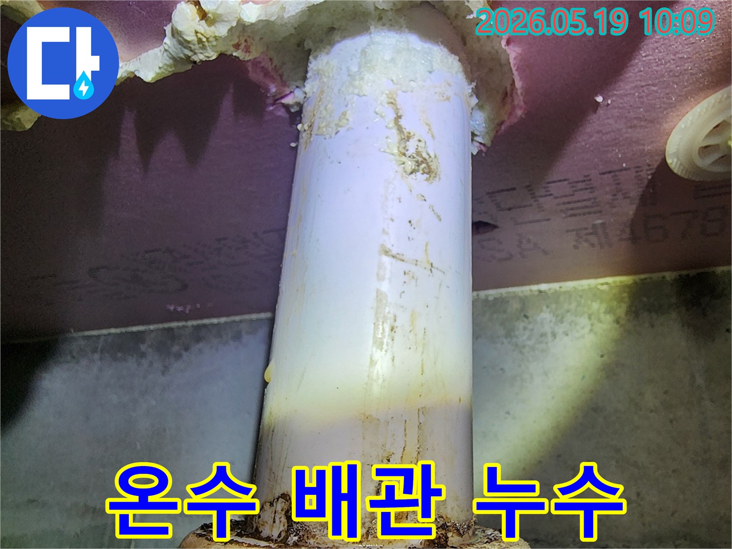 이 이미지는 온수 배관에서 발생한 누수로-주변이 젖고 오염된 모습을 보여줍니다