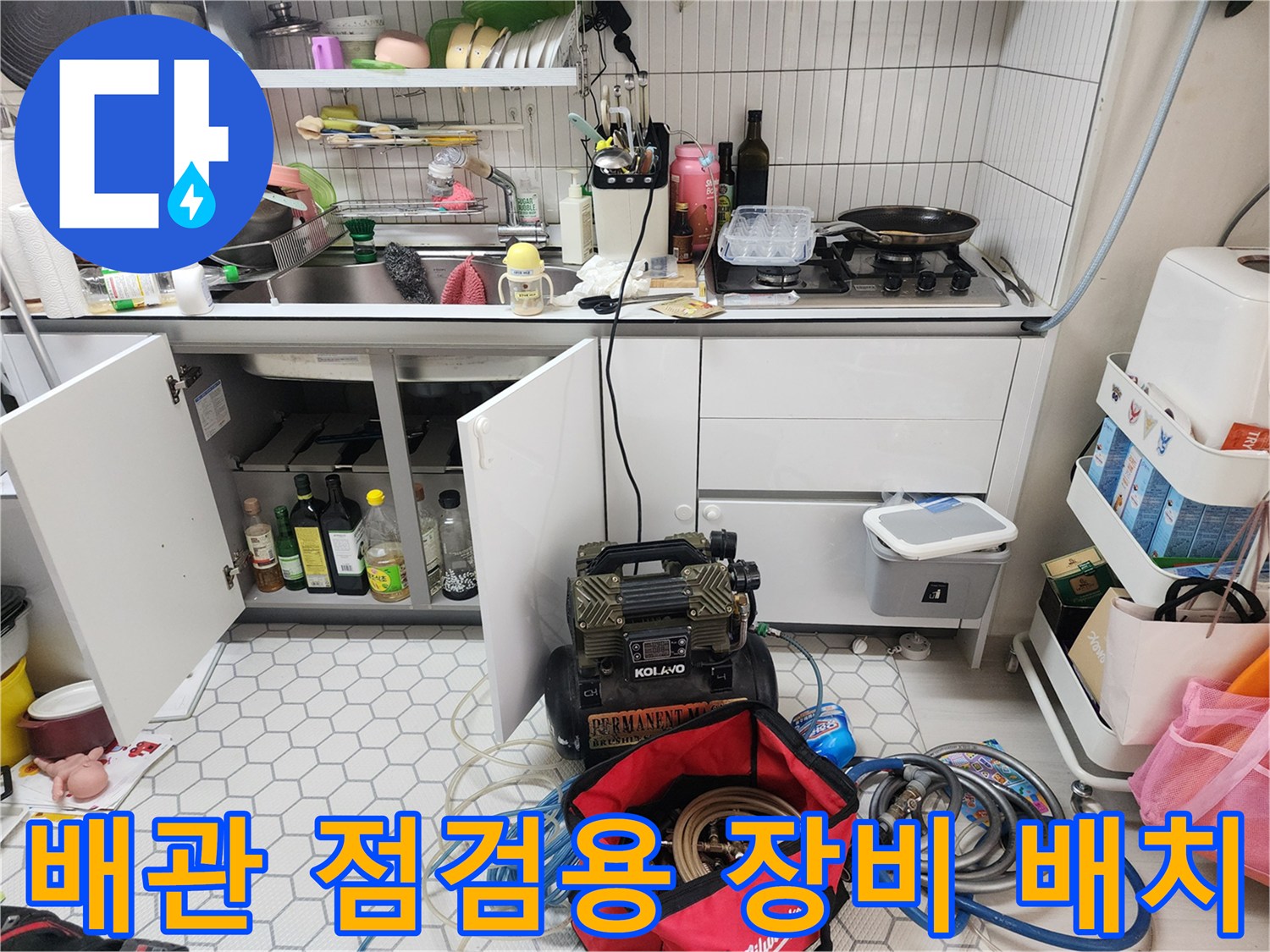 누수 탐지를 위해 싱크대 밑에 설치된 전문 검사 장비와 공구들