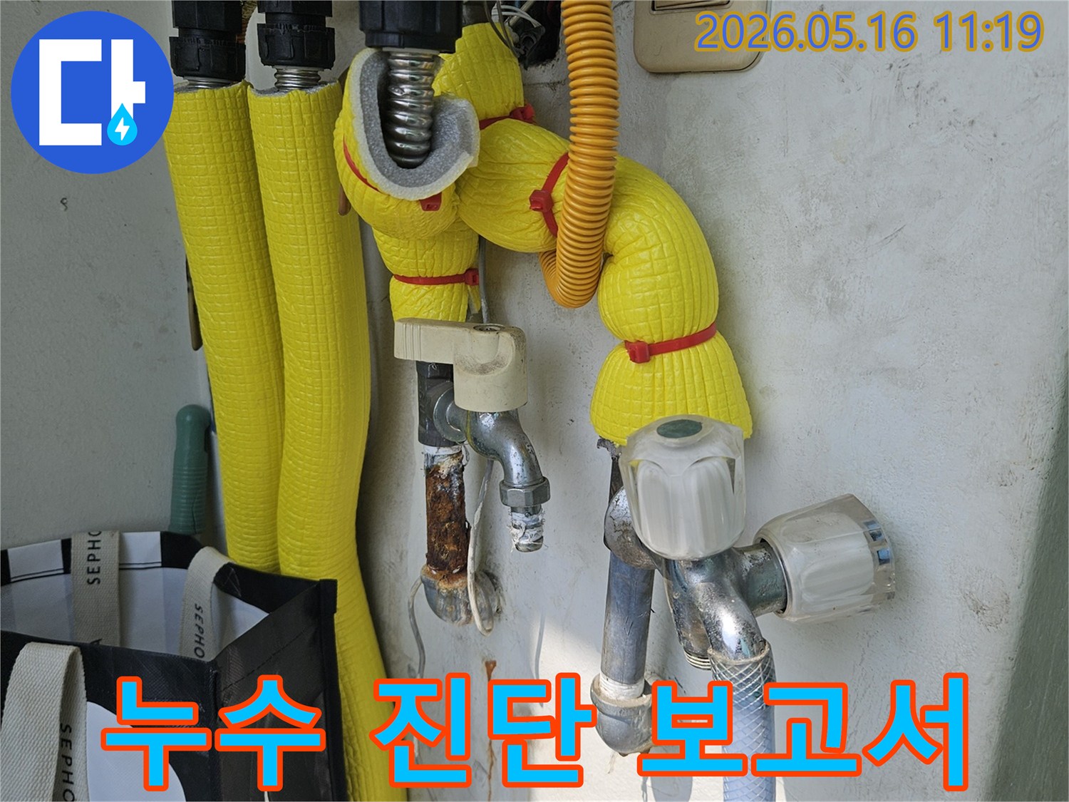 이 이미지는-강동구 길동 아파트 베란다에서-수도 배관 누수 진단 후-전문적인 보고서 작성을 위해-현장을 기록하는 모습을 보여줍니다.
