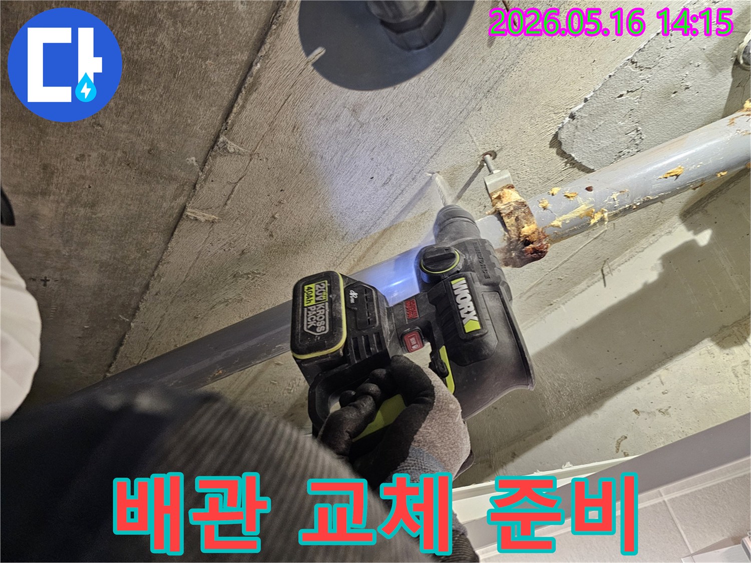 누수 전문가가 노후된 배관 교체를 위해 천장 콘크리트를 드릴로 제거하는 모습-안전하고 정확한 작업을 위한 준비 단계입니다.
