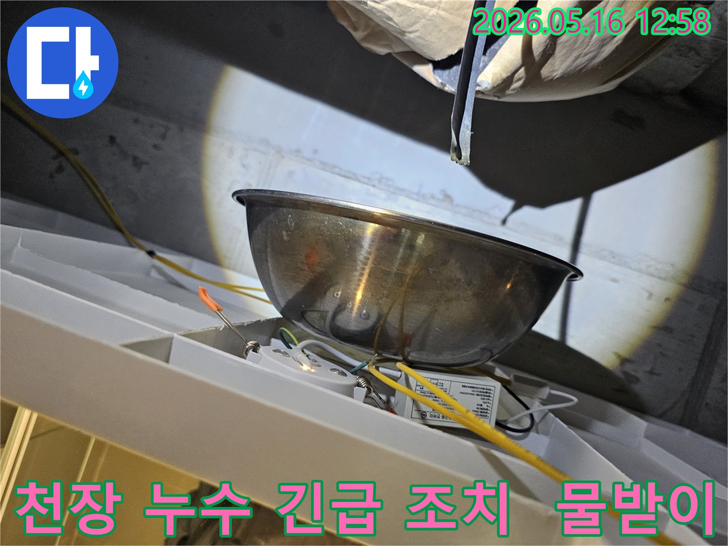 천장에서 물이 떨어지는 것을-스테인리스 볼로-받아내며-주변의 전기 배선과-조명 장치를-보호하는 긴급 조치 현장