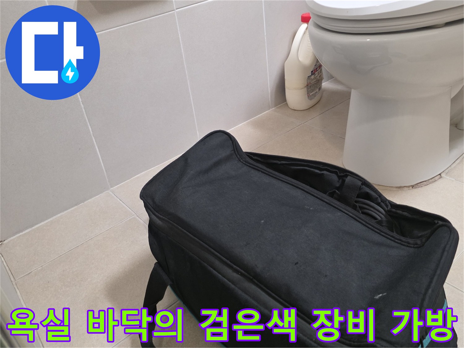 변기 옆 타일 공간에 놓인 검정색 작업용 케이스