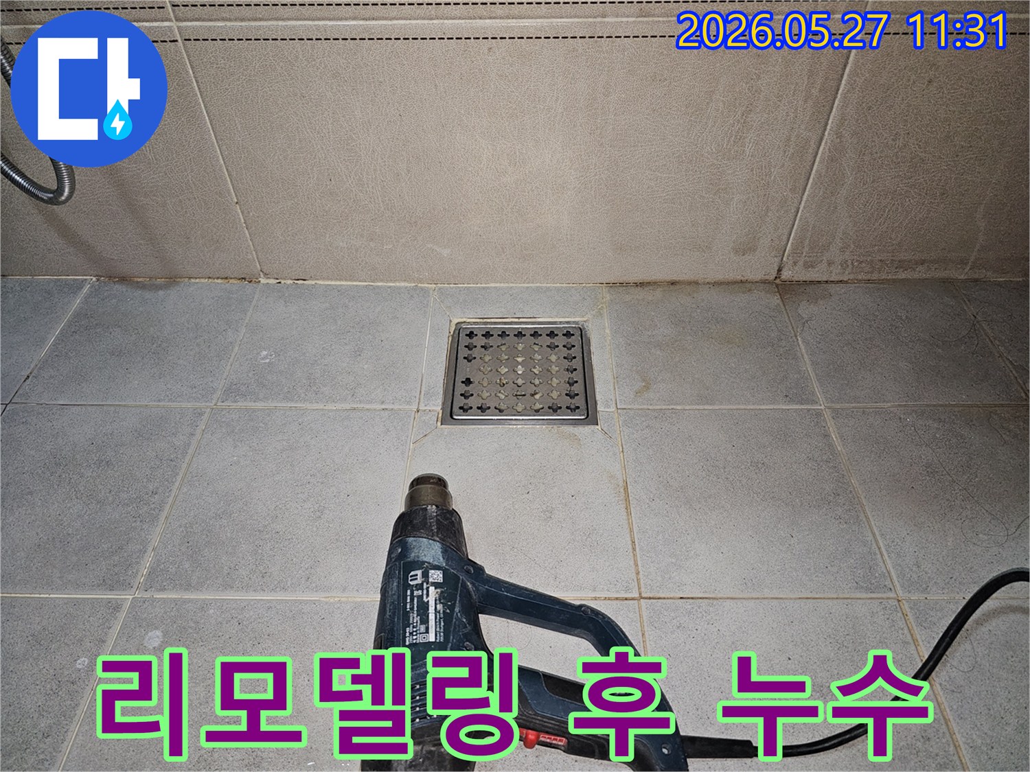 누수 엔지니어가-욕실 리모델링 후 발생한 누수 점검을 위해-배수구 주변을 열풍기로 건조하고 있습니다