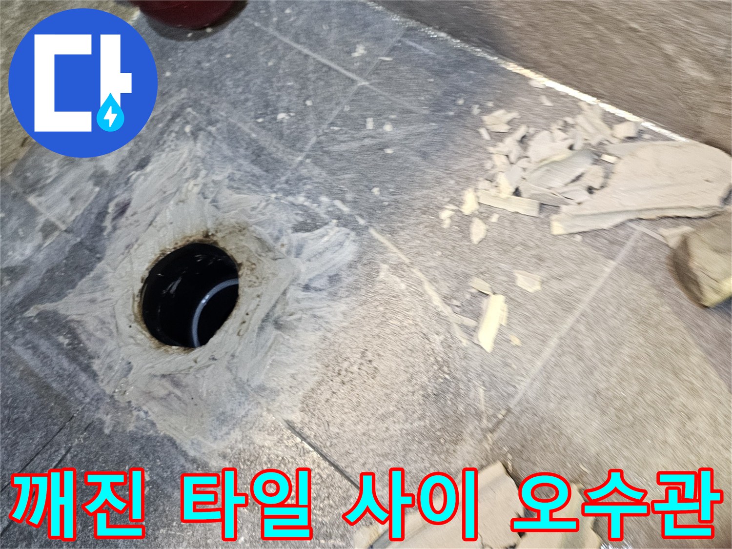 오수관 주변의 깨진 타일과 노출된 배관 입구 사진입니다.