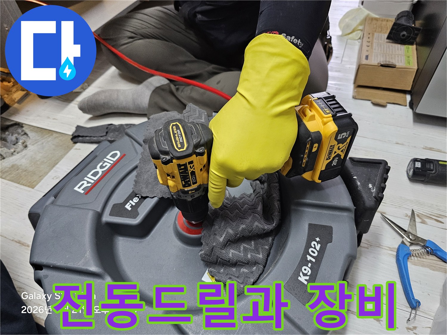 노란색 작업용 장갑을 낀 엔지니어가 전동 드릴을 사용해 작업 중인 모습