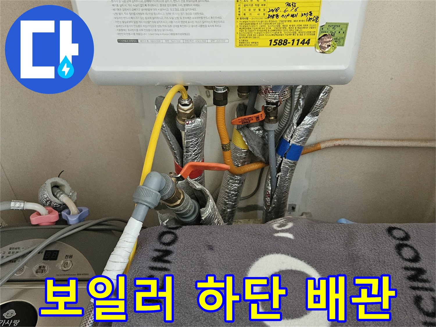 보일러 아래쪽으로 연결된 여러 종류의 급수 및 온수 배관들