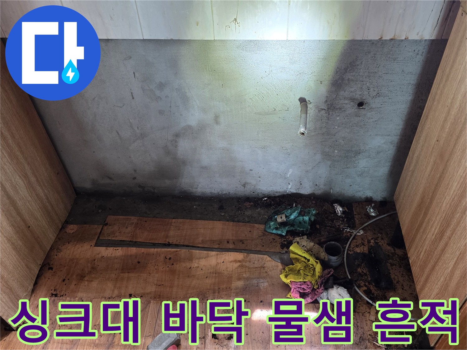 싱크대 하부장 내부-물에 젖어 변색된 바닥판과 배관 주변 상태