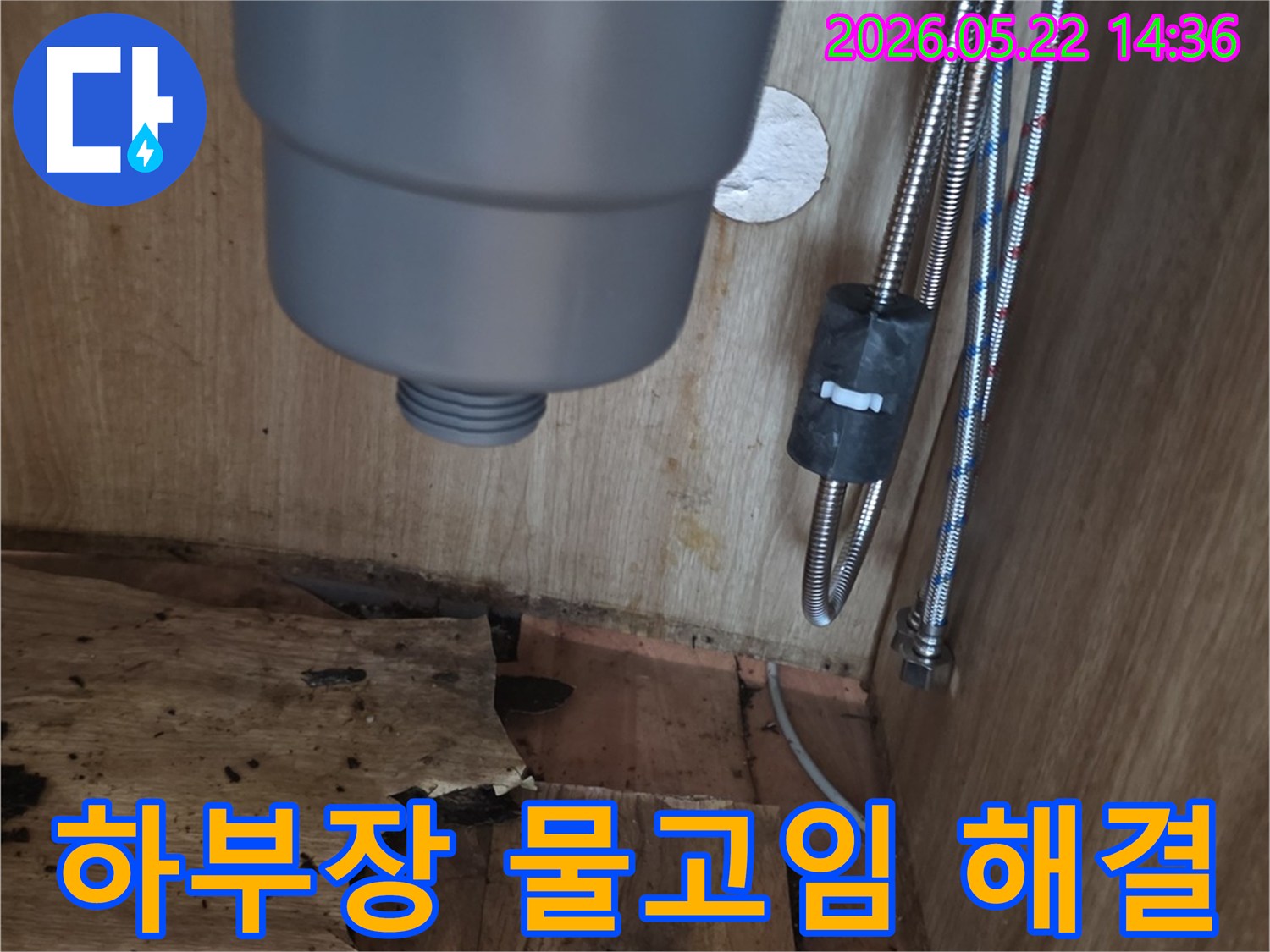 싱크대 하부장 바닥에 고인 물과-물에 젖어 손상된 목재-그리고 배관의 모습을 보여주는 누수 해결 현장
