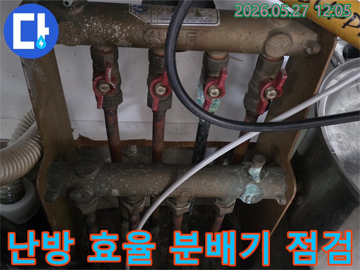 오래된 아파트의 보일러 분배기에서-난방 효율 저하의 원인을 찾기 위해-전문가가 배관과 밸브 상태를-점검하고 있는 모습입니다