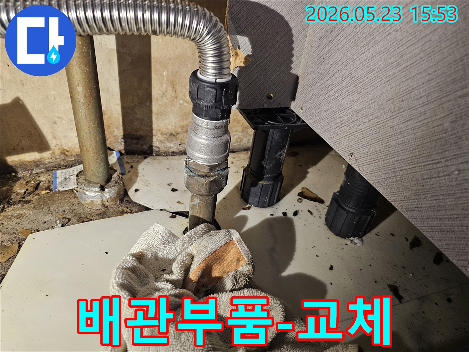 싱크대 배관 연결부에서 물이 새어-바닥에 젖은 수건이 놓인-부품 교체 현장 사진