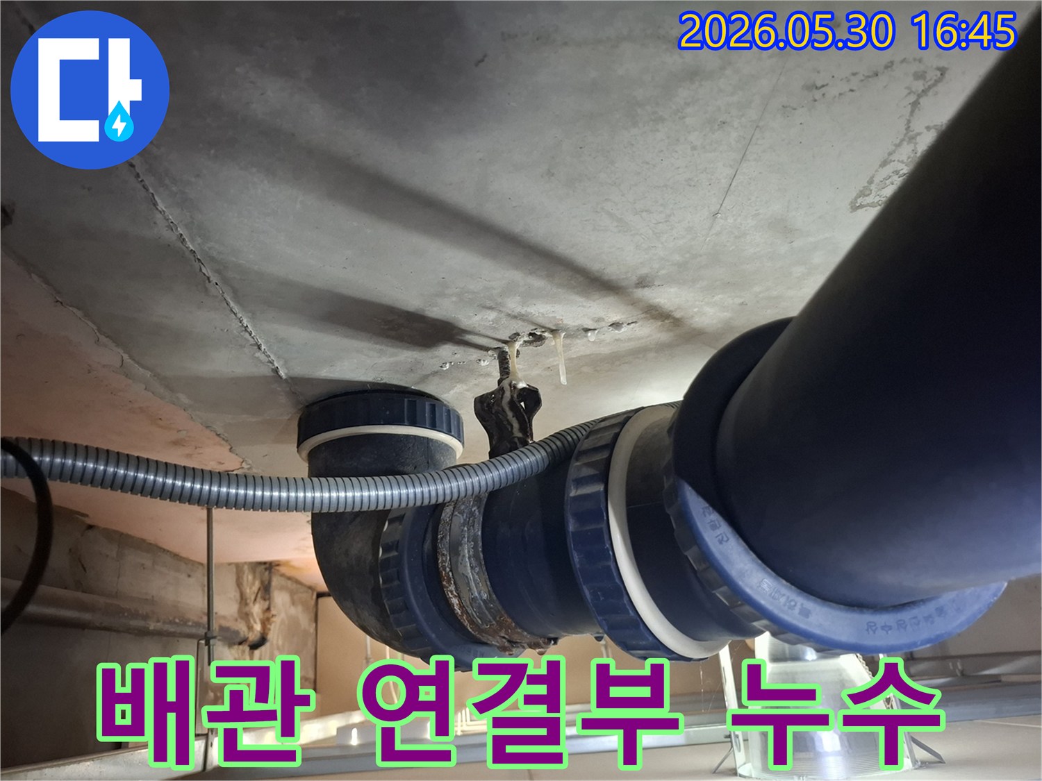 콘크리트 천장 아래-설치된 배관의-연결 부위에서-물이 새어 나와-천장에 얼룩을-만드는 모습입니다.