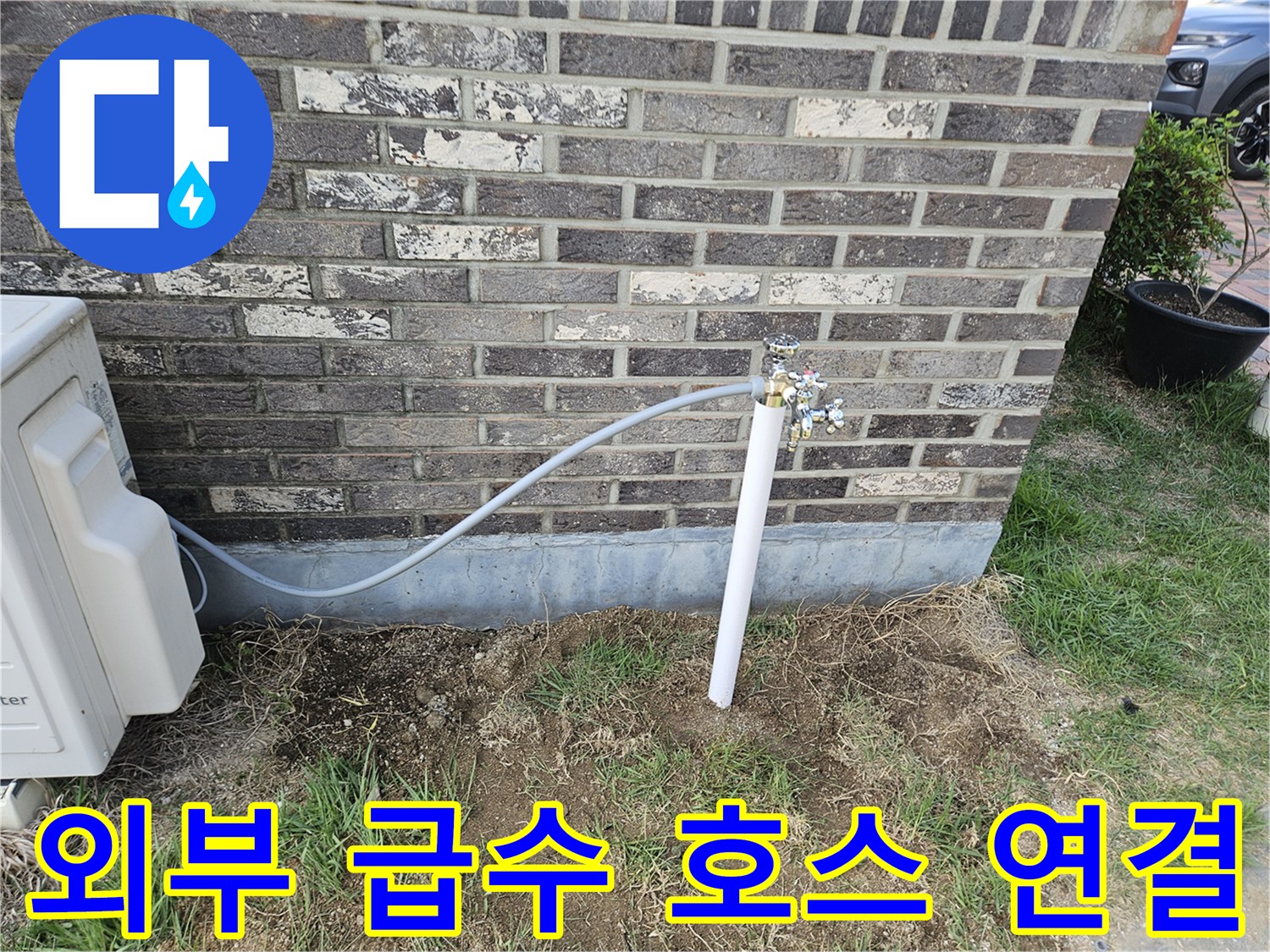 벽돌 외벽에 설치된 외부 수도꼭지와 긴 호스 연결 상태