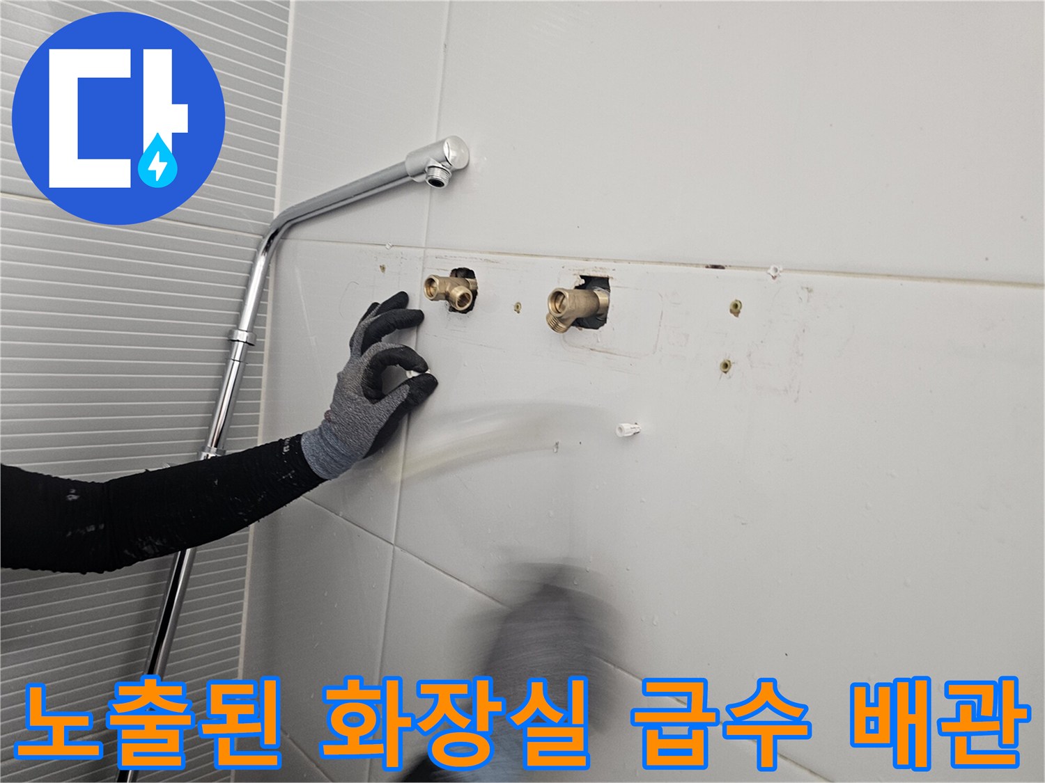 욕실 타일 뒤쪽으로 드러난 금속 재질의 수전용 배관 부위