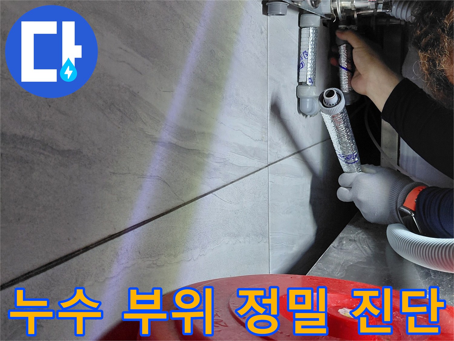 어두운 싱크대 밑 공간에서 진행되는 배관 누수 점검 작업