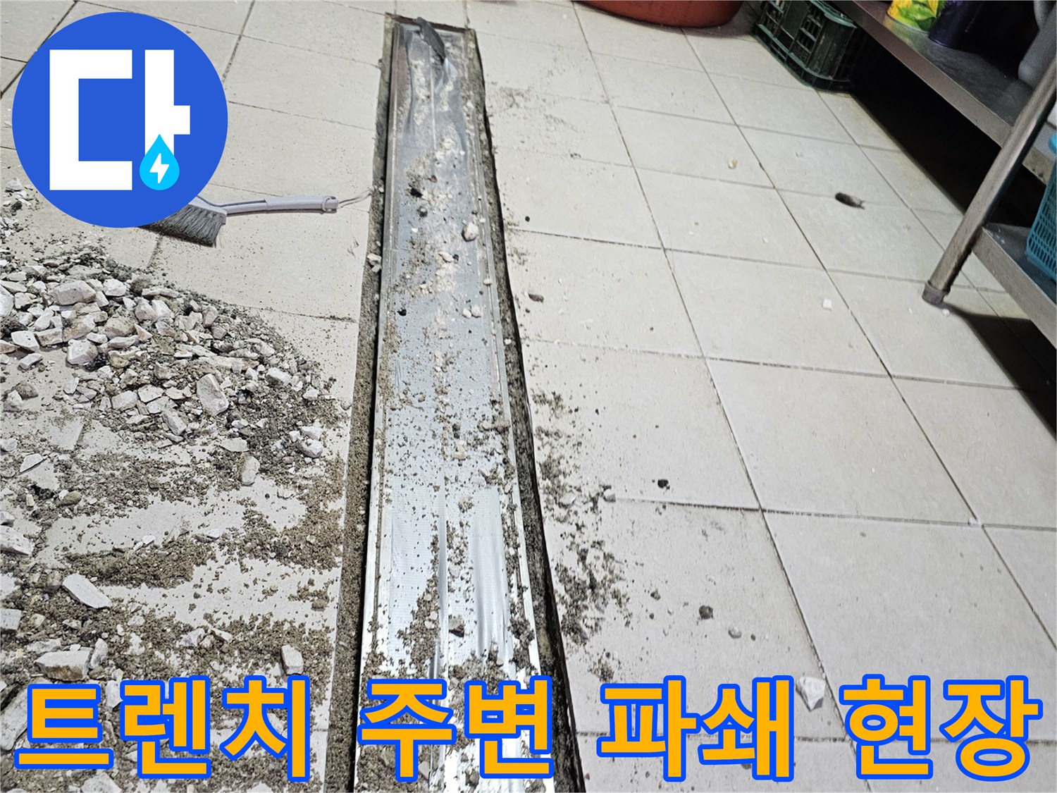 식당 주방 배수 트렌치 주변의 타일과 덮개를 제거한 보수 작업 모습입니다.