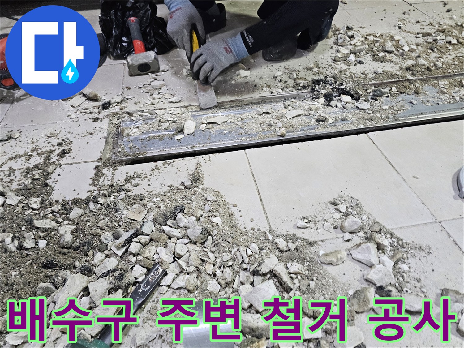 트렌치 배수구 근처의 타일과 시멘트를 제거하는 현장 사진입니다.