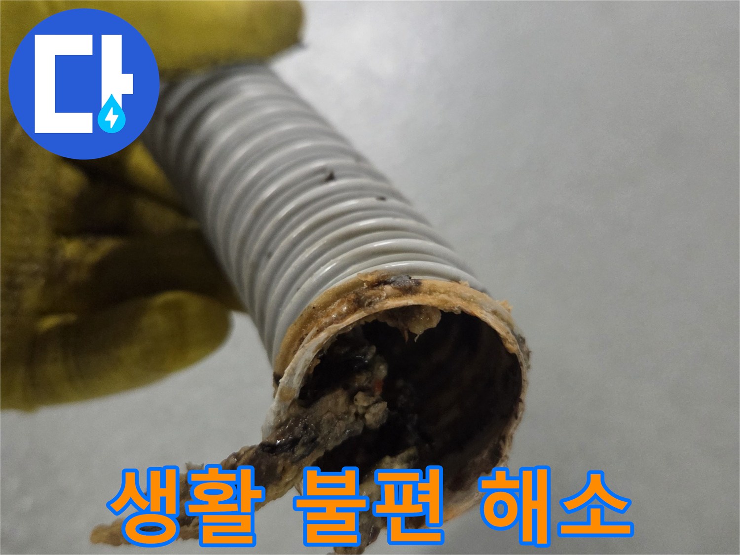 노란 장갑을 낀 작업자의 손이-오염된 배수관을 들고-문제 해결을 준비하고 있습니다.