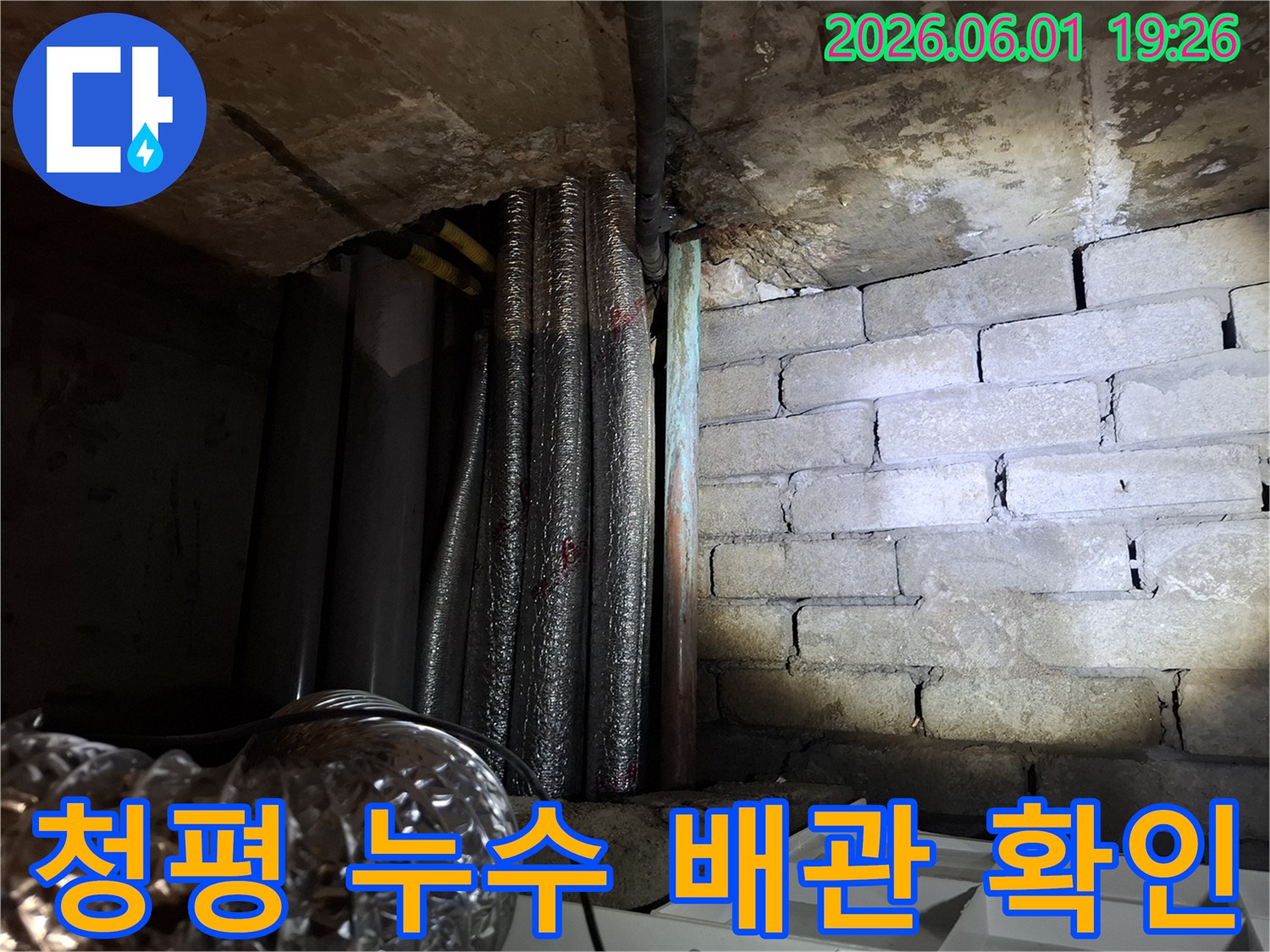 습하고 어두운 지하 공간에서-천장 배관과-벽돌 벽면의-누수 흔적을-자세히 보여주는 이미지입니다