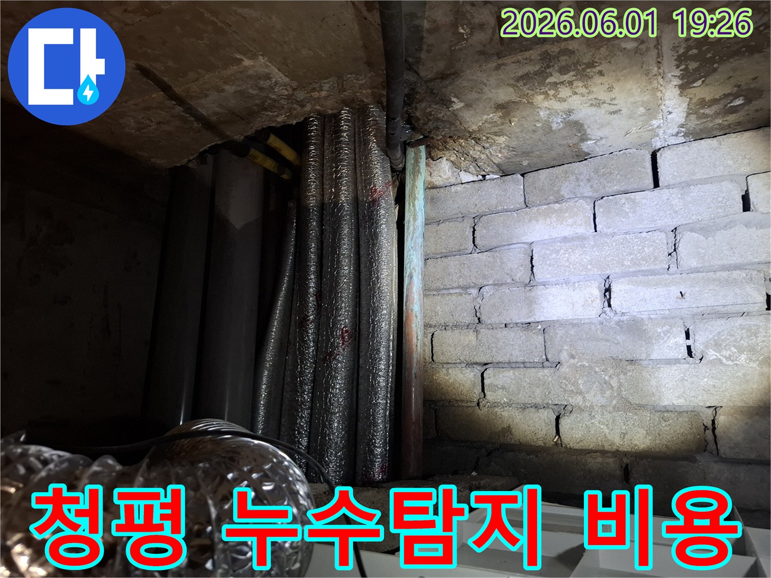 어두운 지하 공간에서-천장 배관과-벽돌 벽면의-누수 흔적을-확인하는 모습의-누수탐지 현장 사진입니다