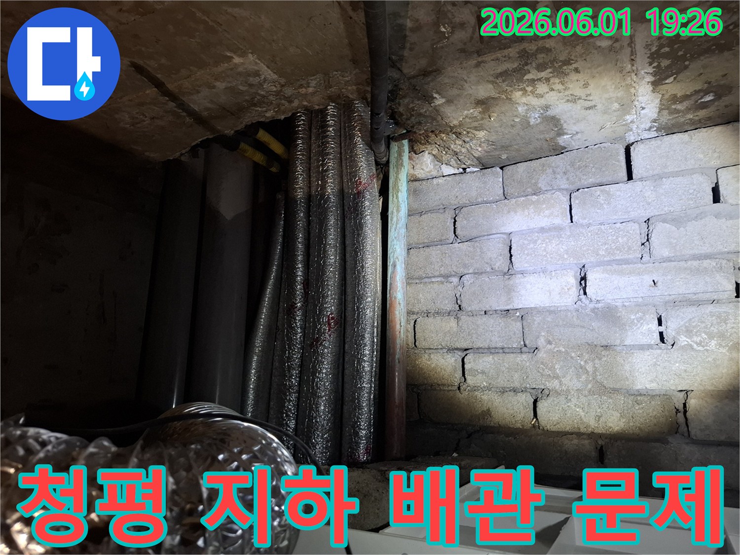 어두운 지하 공간에서-천장 배관과-벽돌 벽면의-누수 흔적을-확인하는 모습의-누수탐지 현장 사진입니다