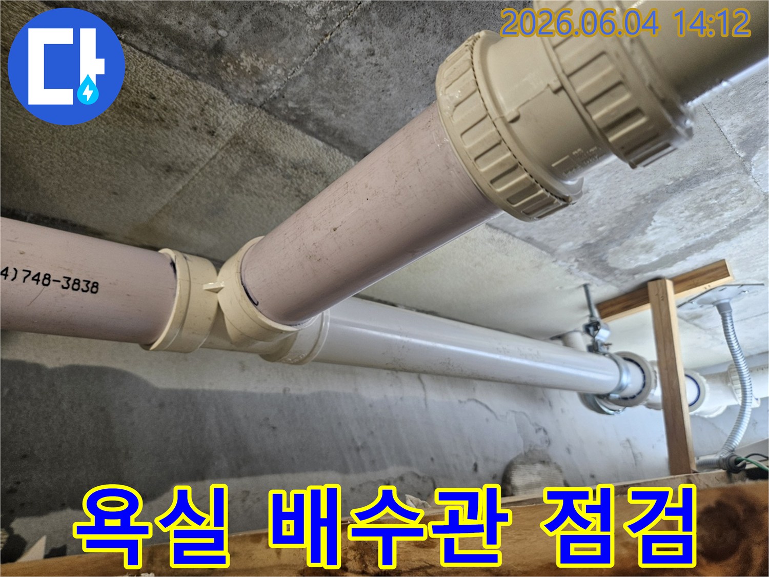 욕실 천장 아래로 지나가는 배수관의 연결부위에서 누수 흔적이 발견되어-전문가가 점검 및 보수 작업을 진행하는 모습입니다