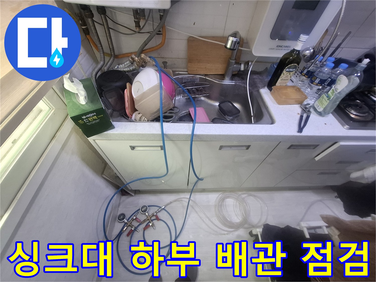 주방 싱크대 하부의 수도 배관과 압력 측정 장비가 연결된 모습