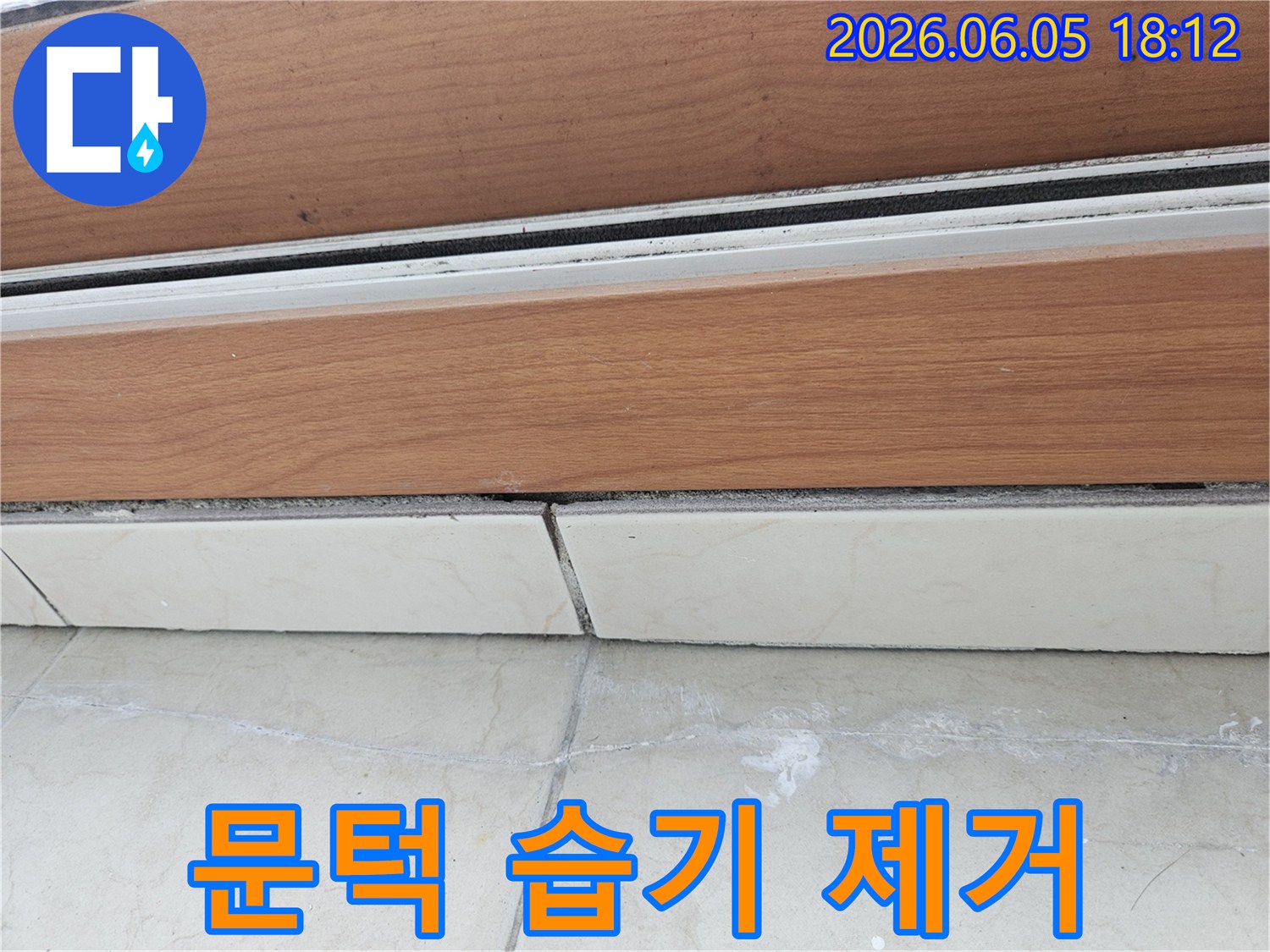 문턱-하단과-타일-경계선에-보이는-습기-흔적을-제거하고-건조-처리하기-위한-계획을-세우는-모습