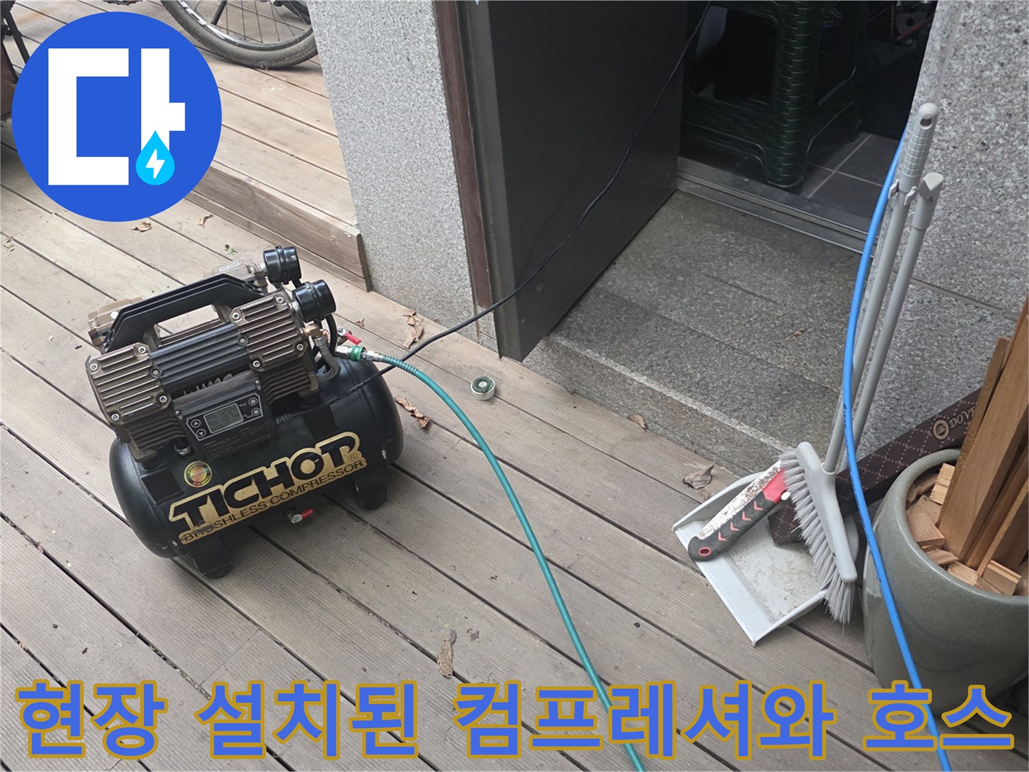 나무 데크 위 에어 컴프레셔와 파란색 공압 호스 연결 상태