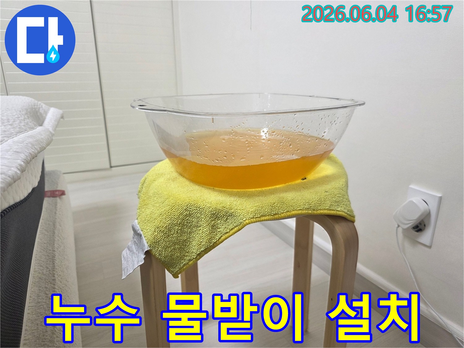 천장에서 물이 떨어지는 긴급 상황에서-바닥 손상을 막기 위해-설치된 임시 물받이와-노란 수건의 모습