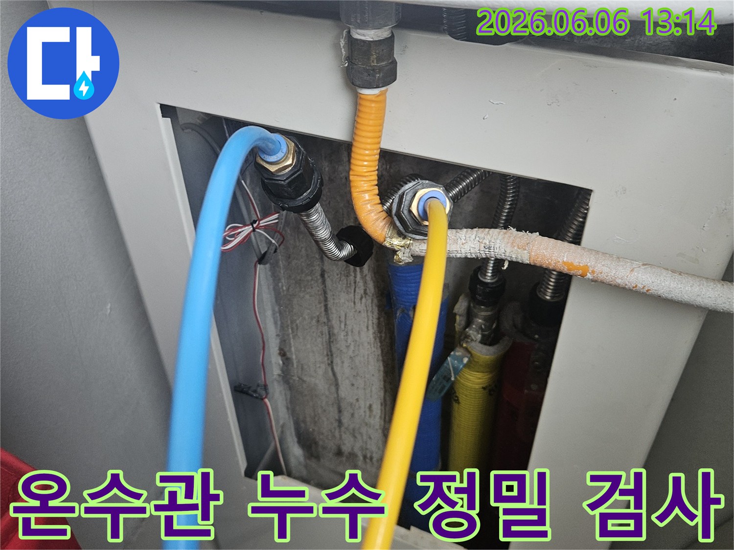 보일러 하단에 연결된 뜨거운 온수관의 연결 부위에서-누수 지점을 정밀하게 검사하고 원인을 파악하는 모습