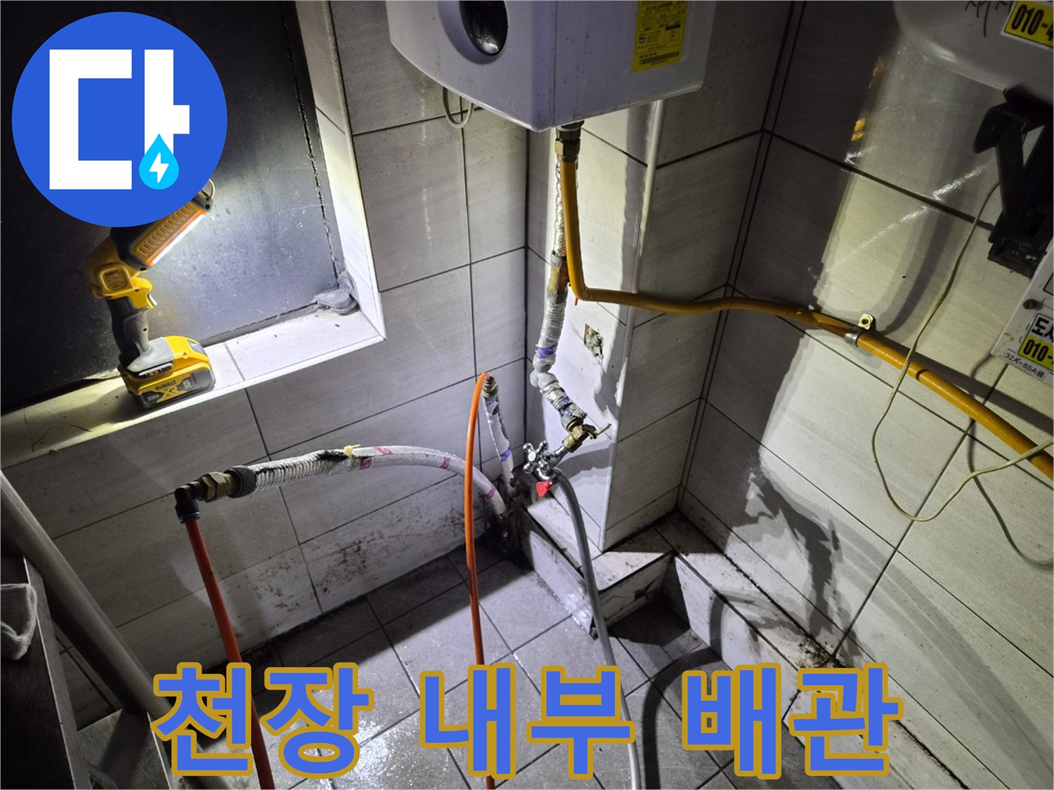 타일 벽면과 노란색 배관 및 작업용 전동 드릴 배치 상태