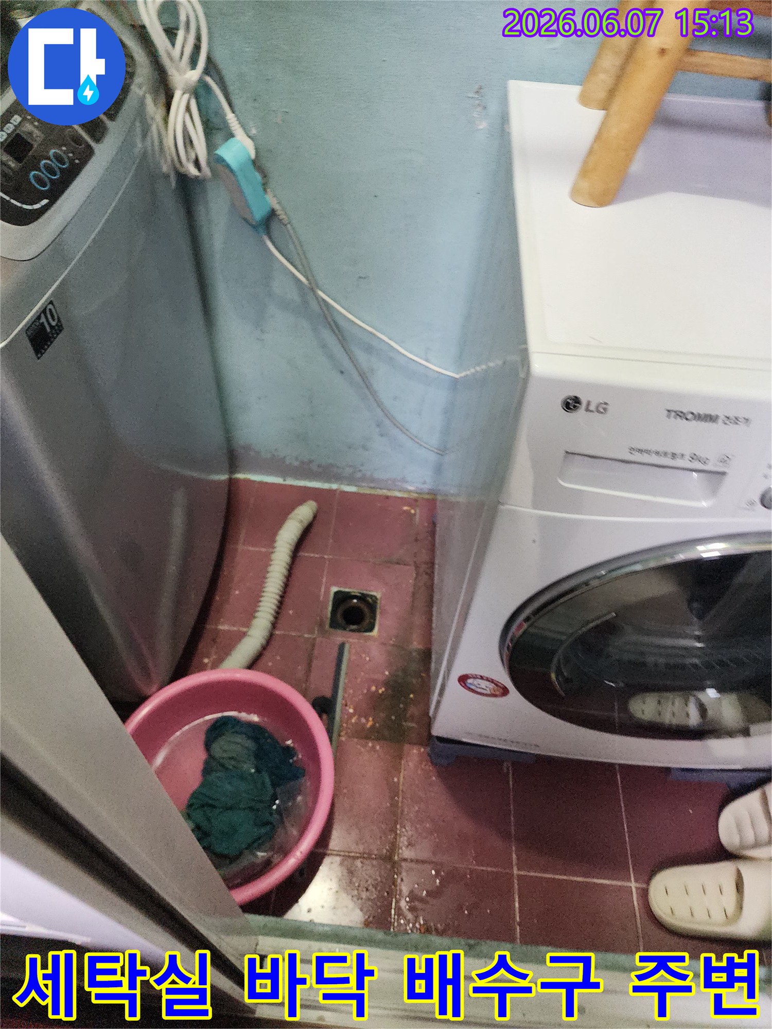 세탁기와 세탁기 사이 좁은 공간의 배수구와 물이 고인 듯한 바닥 모습입니다.
