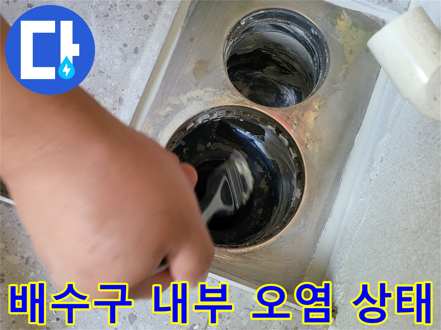세탁실 하수구 안쪽의 젖은 흔적과 이물질을 점검하는 모습