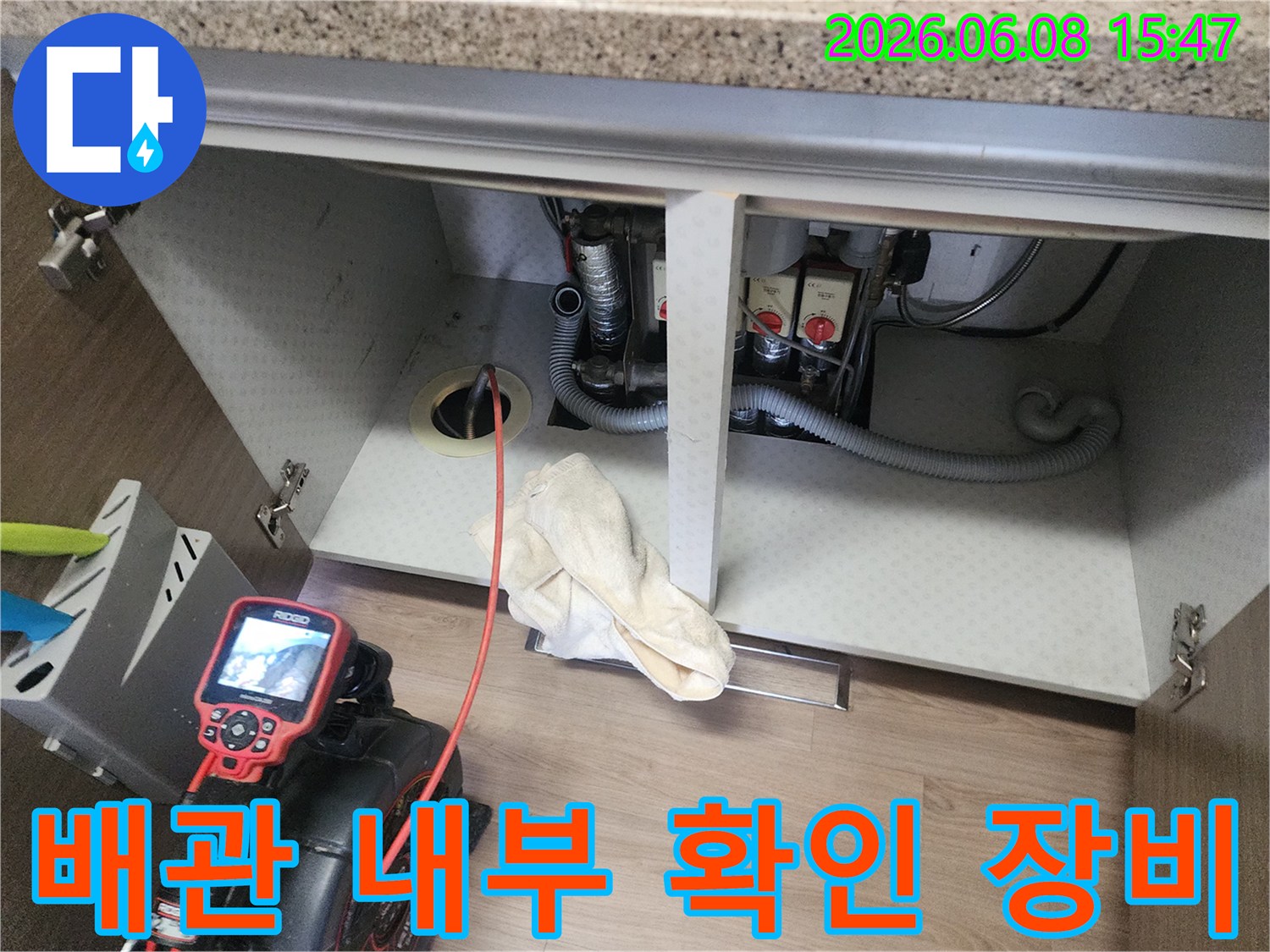 내시경 모니터와 배관으로 연결된 케이블이 싱크대 하부에서 작업 중인 모습입니다.