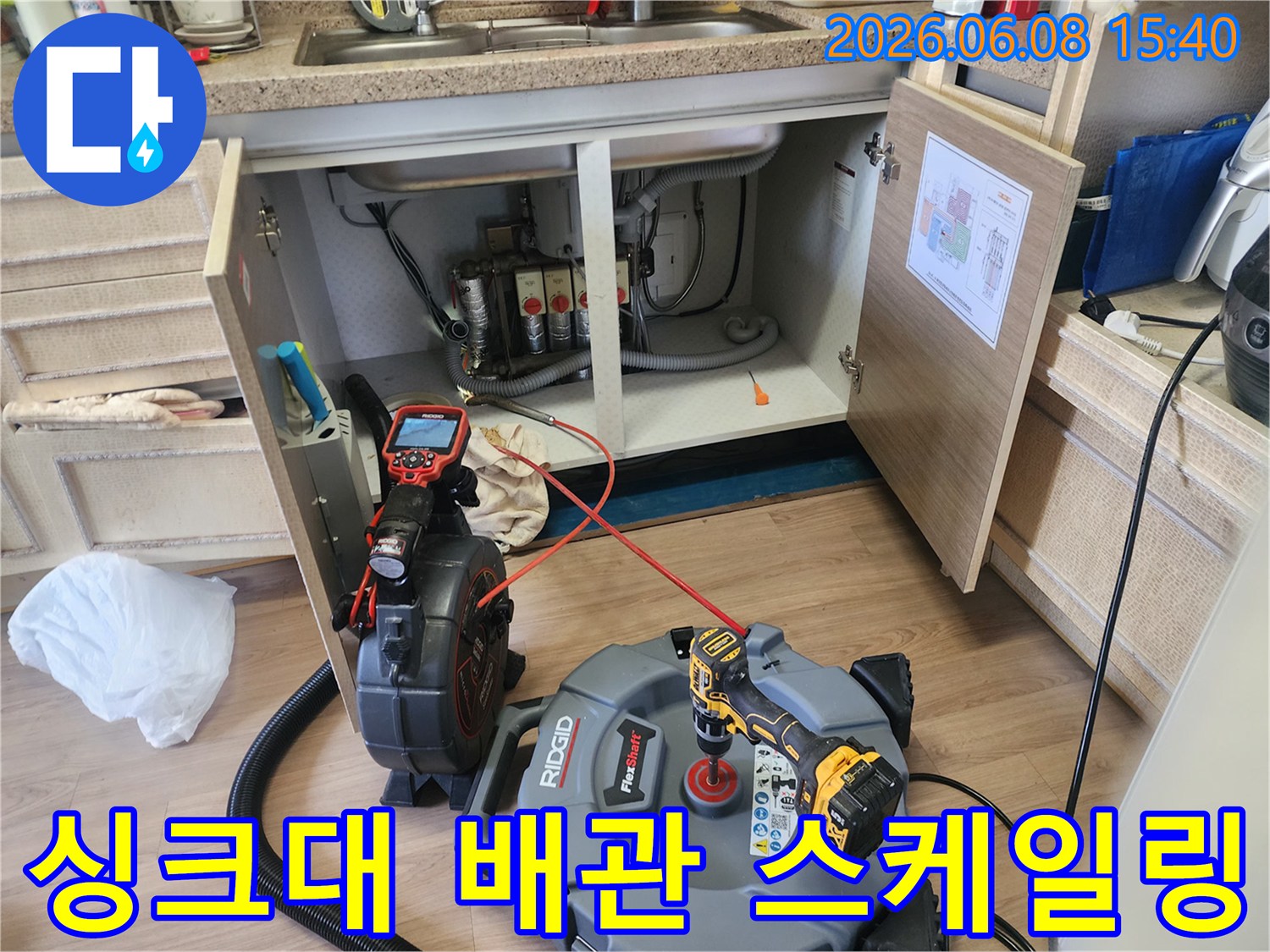 싱크대 하부장 아래 배관 청소를 위해 준비된 내시경 카메라와 스케일링 장비 세트입니다.