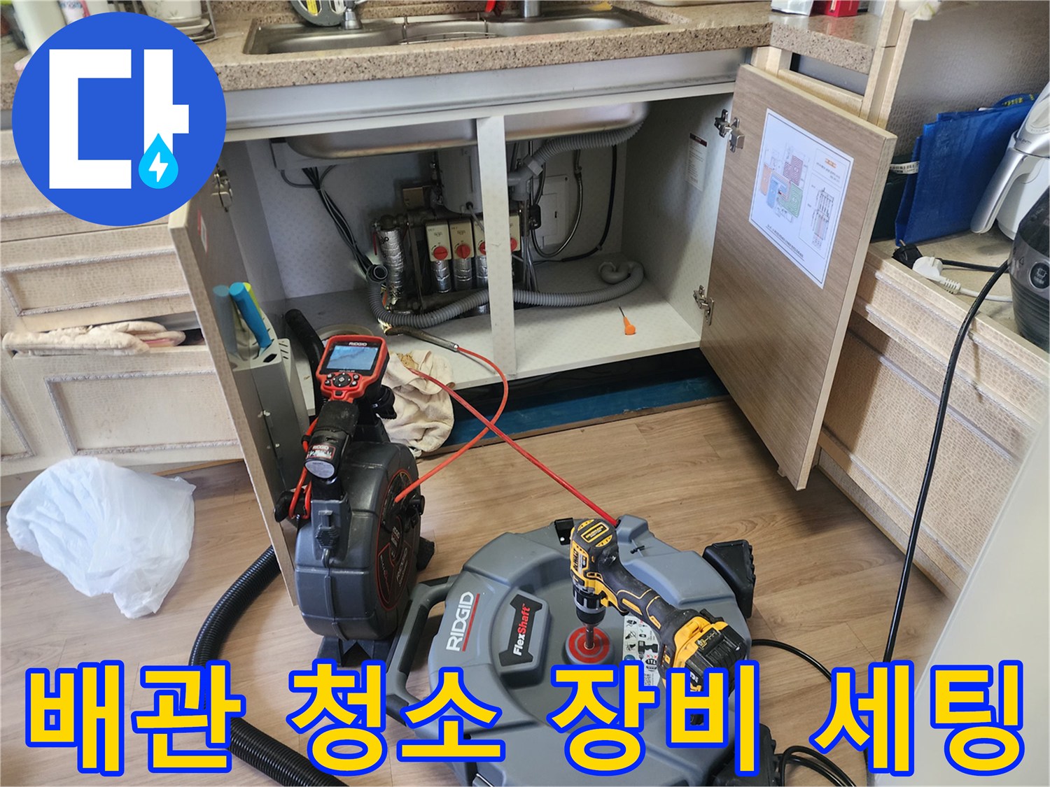하부장 아래 배관 내부를 촬영 중인 내시연 카메라와 작업 도구들