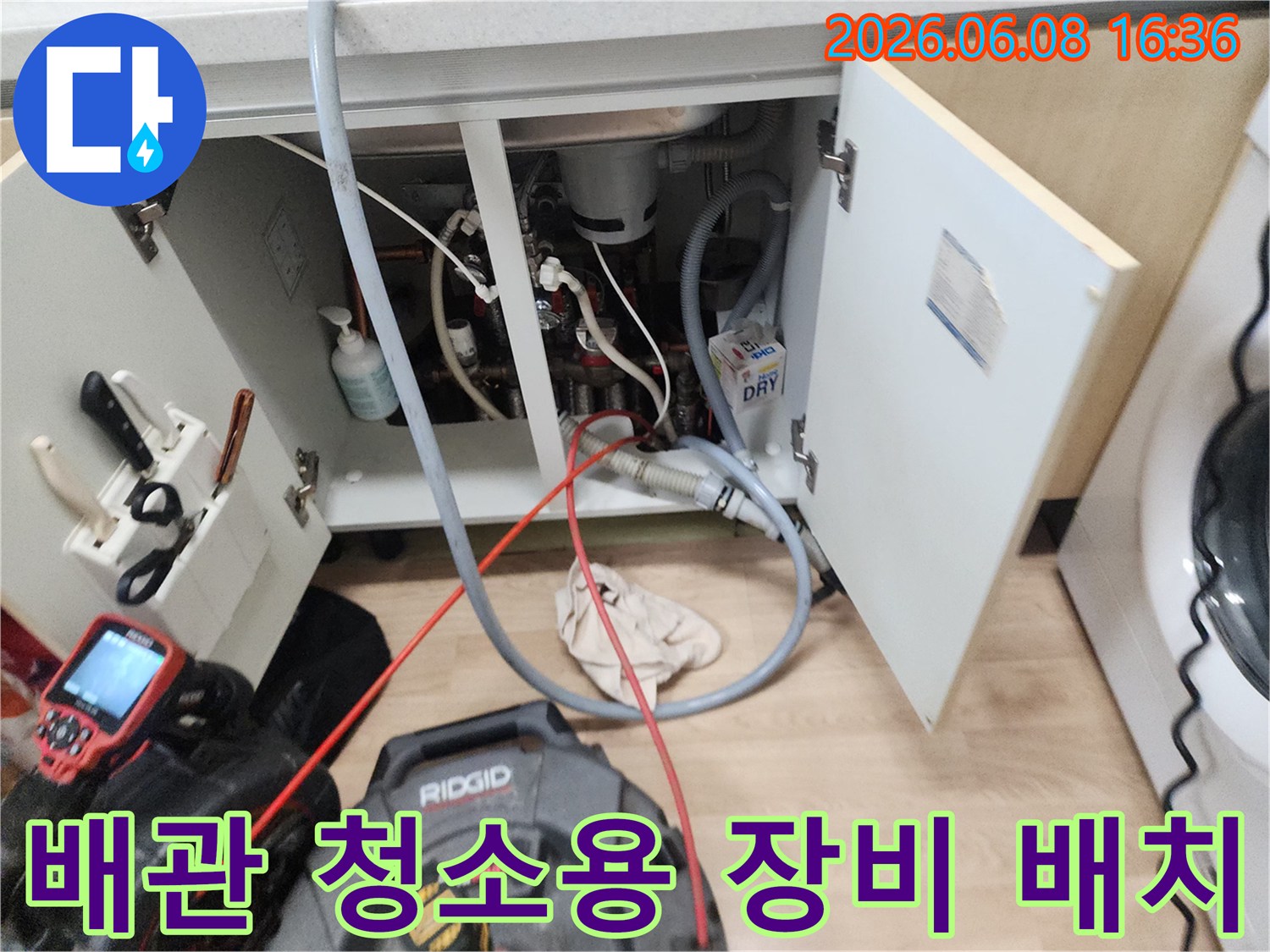 싱크대 하부 배관 작업을 위해 설치된 전문 장비와 케이블