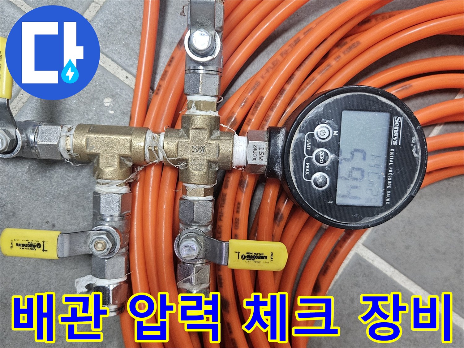 밸브와 호스가 복잡하게 연결된 배관 시스템에 디지털 압력계가 설치되어 있습니다.