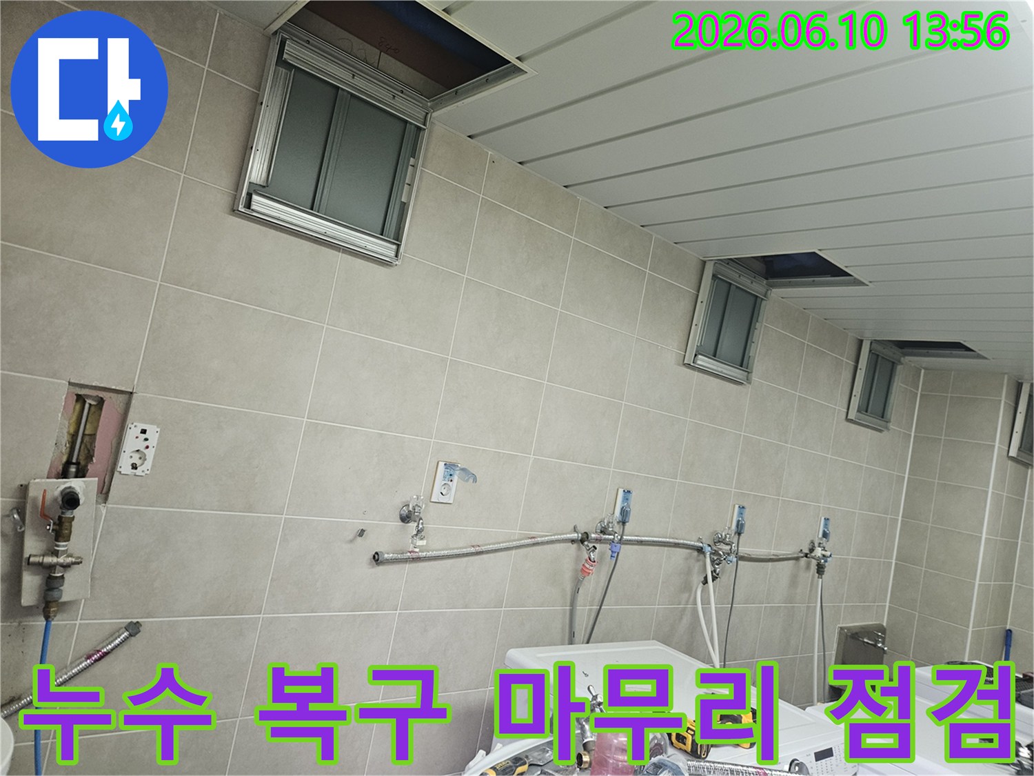 세탁실 천장 점검구와 배관 주변을 다시 한번 확인하며-누수 복구 작업을 위한 최종 점검을 하는-전문가의 모습