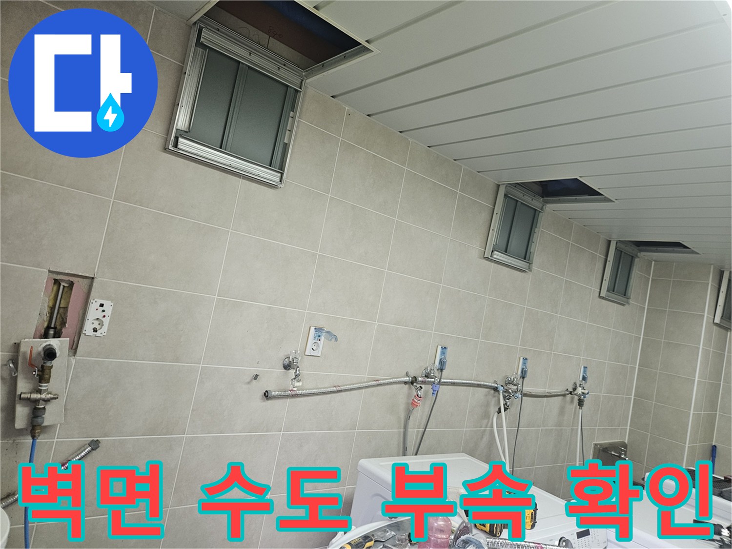 타일 벽면에 설치된 은색 배관과 각종 수전 연결 부위