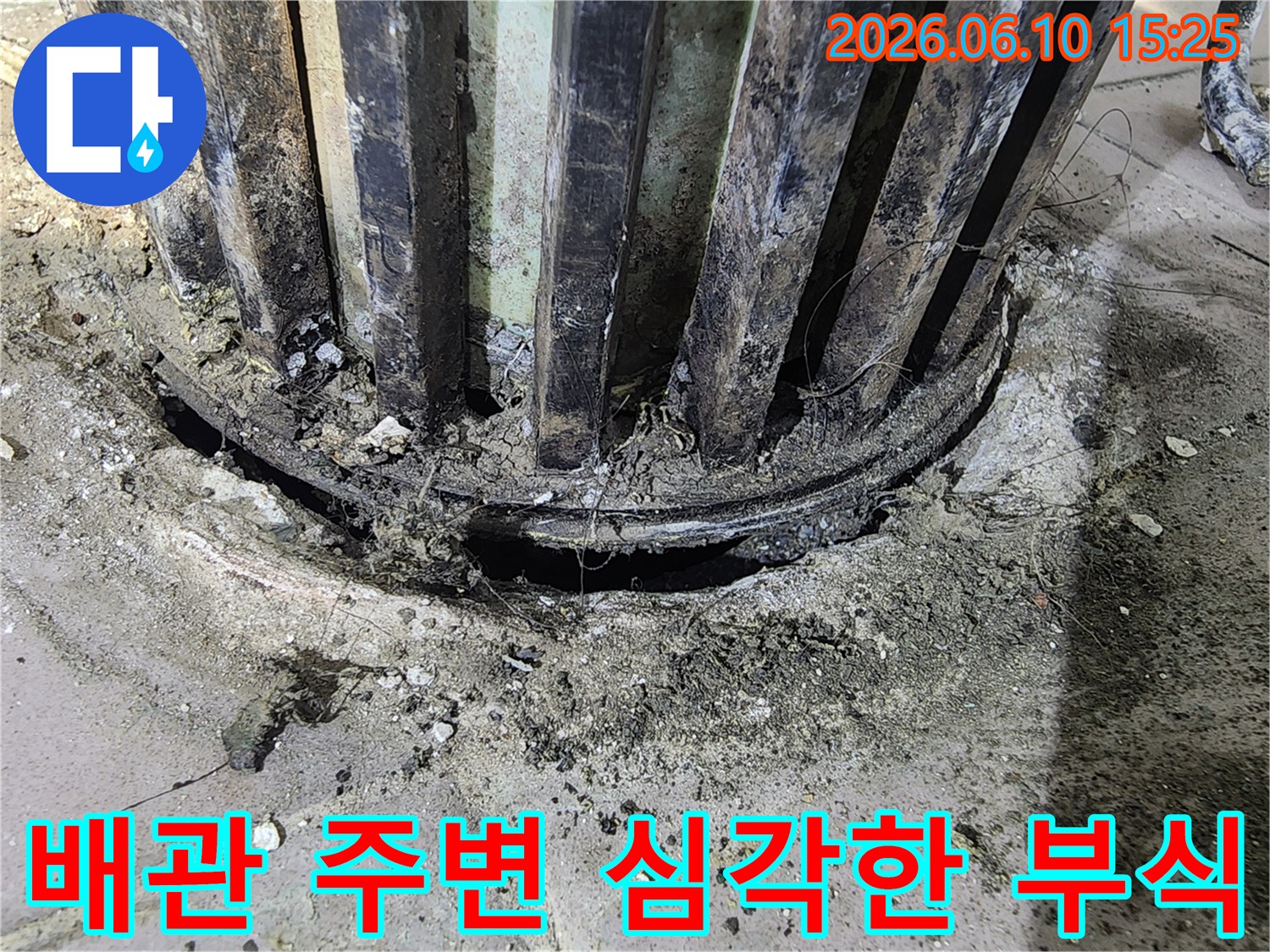 오래된 배관의 심각한 부식과-주변 콘크리트의 손상으로 인한 누수 흔적을 보여주는 사진