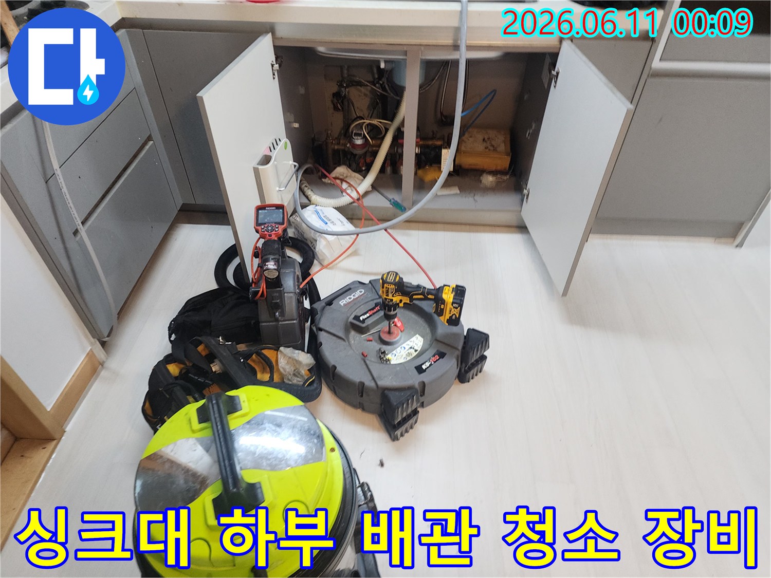 싱크대 밑 배관 근처에 놓인 스케일링 장비와 산업용 청소기