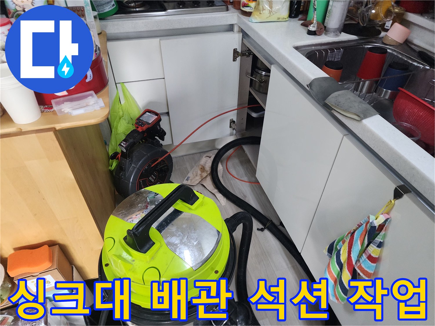 주방 하수구 배관에 석션기를 연결하여 이물질을 제거하는 장면입니다.