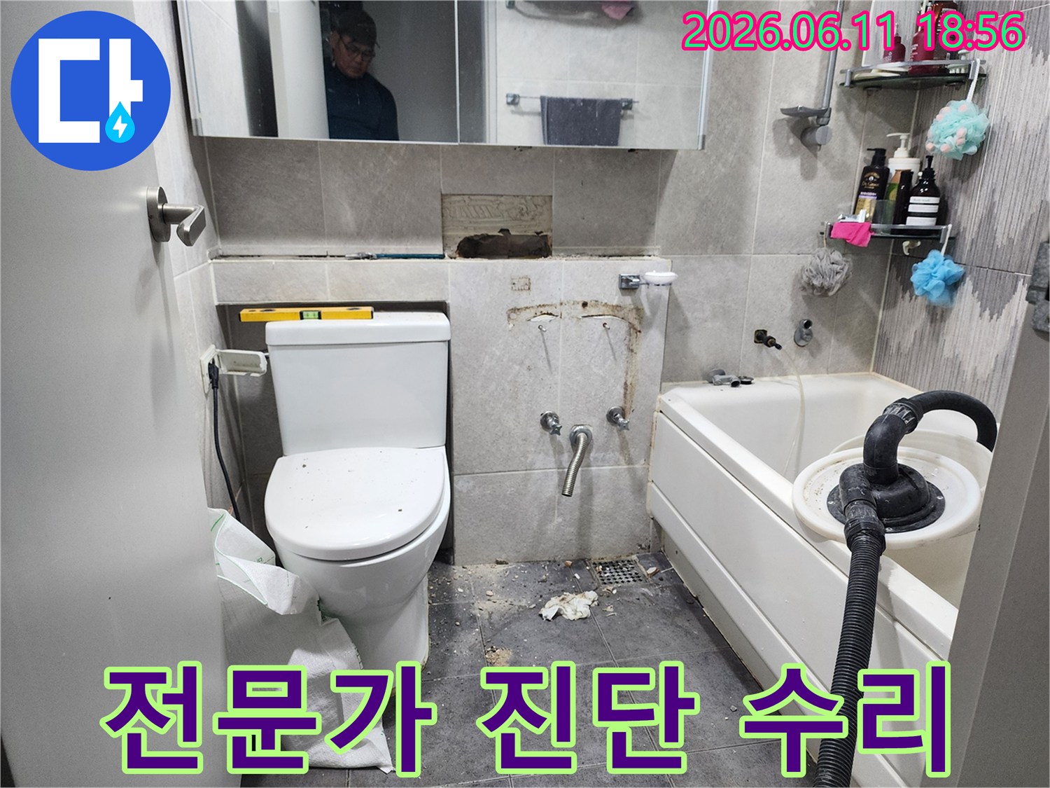 이 이미지는-동대문구 아파트 욕실에서-전문가가 누수 원인을 진단하고-수리하기 위해-타일을 제거하고-배관 상태를 점검하는-작업 현장을 보여줍니다