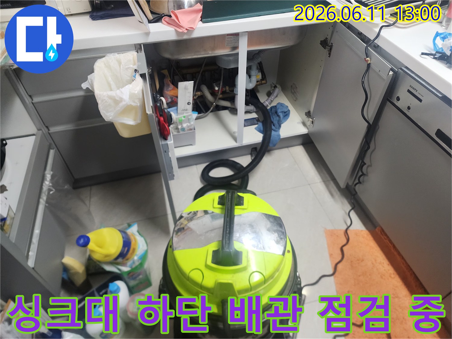 싱크대 아래쪽 배수관과 주변 정리된 청소 장비 모습