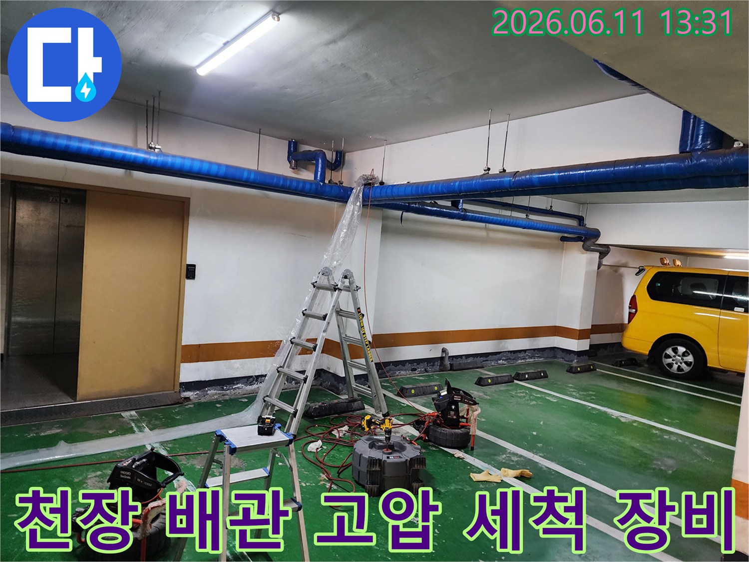주차장 천장에 설치된 파란색 배관과 작업용 고압 세척기